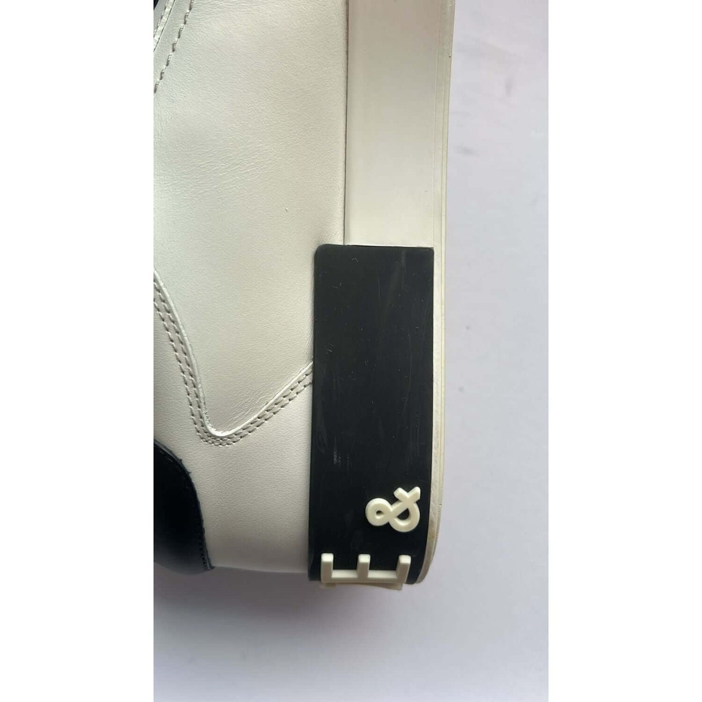 Close-up of Dolce & Gabbana Portofino white leather sneaker with black rubber sole and logo detail, showcasing luxury craftsmanship.